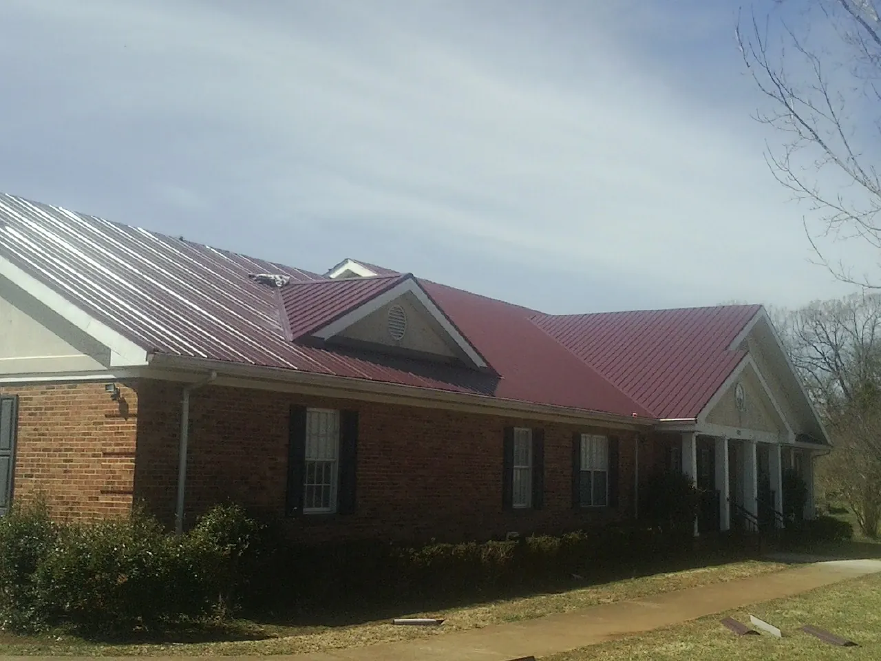 Red metal roof with gabled entries on a long brick building in Lennox