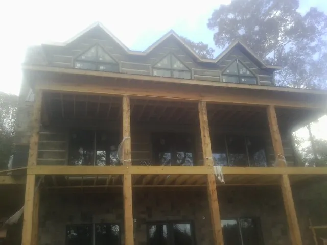 Dormers and porch framing on a large log home under construction — Roof Coating work by our crew in Lennox
