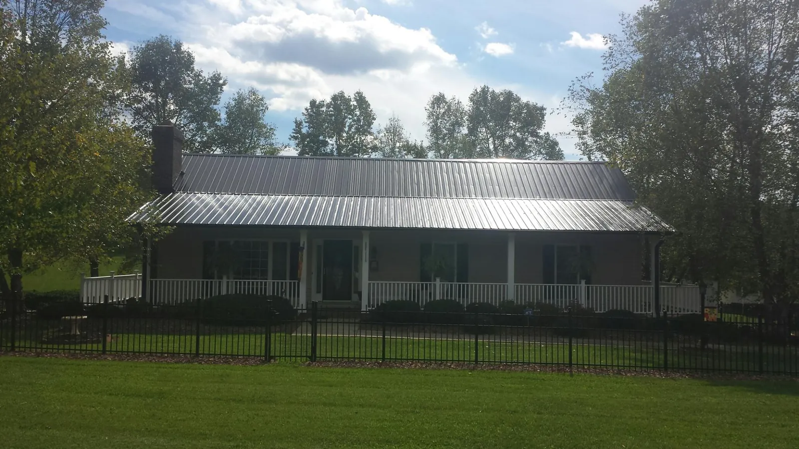 Gray metal roof on a brick ranch with a full width front porch — Gutter Guard Installation work by our crew in Lennox