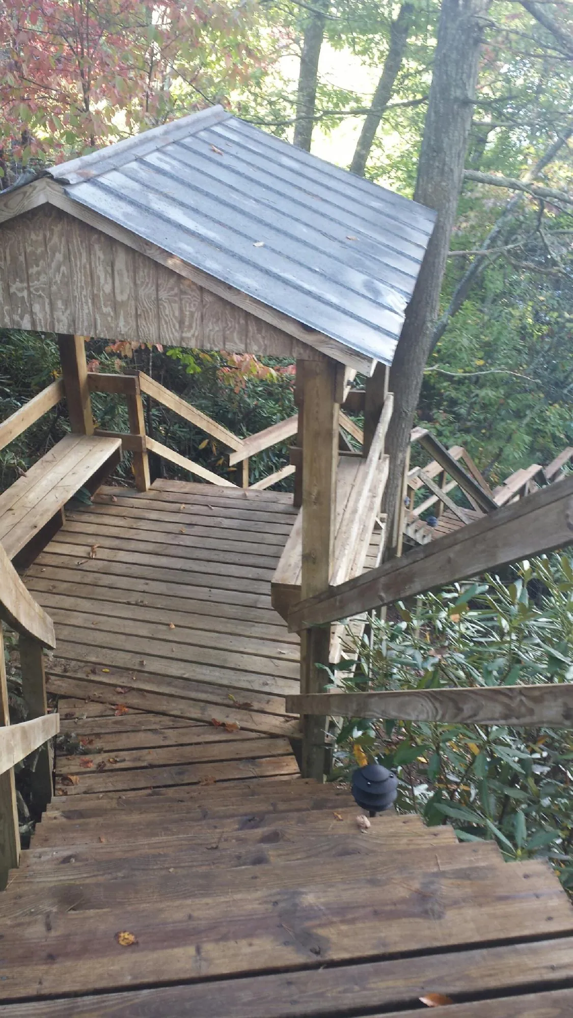 Metal roofed shelter over wooden steps on a wooded walkway — Skylight Repair & Installation work by our crew in Lennox