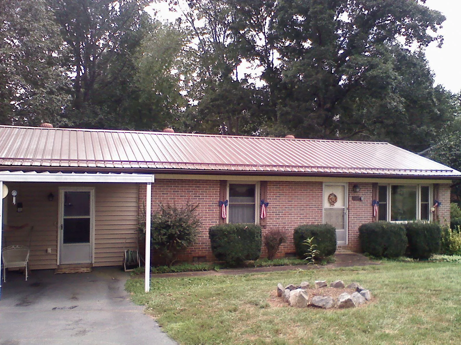 Bronze metal roof and carport on a brick ranch home — Roof Repair work by our crew in Lennox
