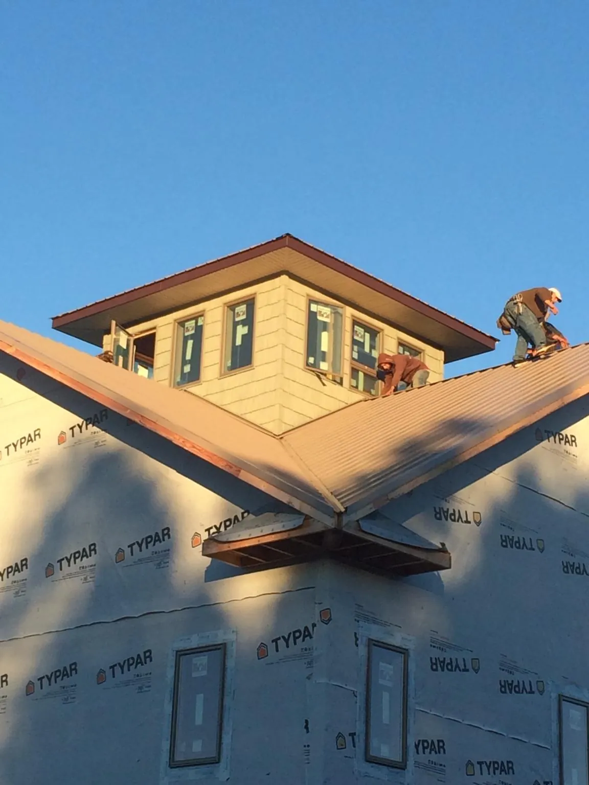 Roofers working around a rooftop cupola on a new metal roof at sunset — Roof Waterproofing in Lennox by Roofing Brothers